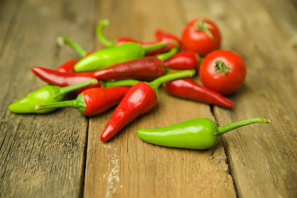 A lot of Chili pepper on old wooden surface — Stock Photo, Image