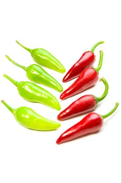 Viele reife rote und grüne Chilischoten auf weiß — Stockfoto