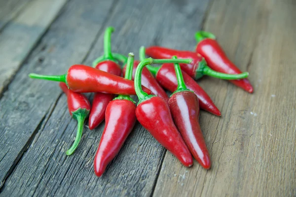 A lot of Chili pepper on old wooden surface — Stock Photo, Image