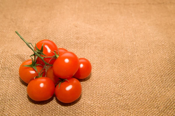 Bunch of red cherry tomatoes on old cloth — Stock Photo, Image