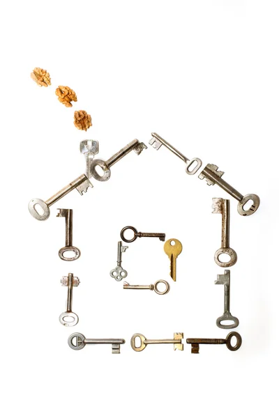 As chaves põem-se na forma da casa em um contexto branco — Fotografia de Stock