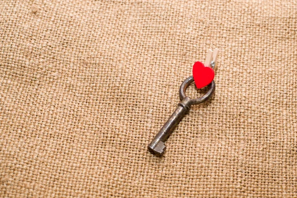 One Vintage key and a red heart on old cloth — Stock Photo, Image