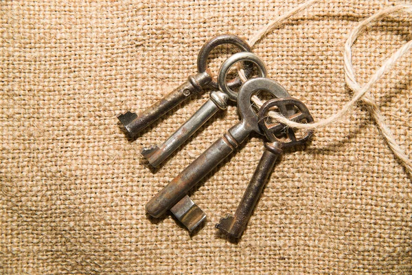 Четыре очень старых ключа, привязанных веревкой к старой ткани. — стоковое фото
