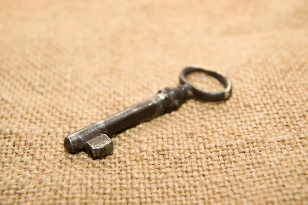 Old key to the safe on a very old cloth — Stock Photo, Image