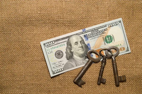 Banconote in dollari USA e chiavi vintage su un vecchio panno — Foto Stock