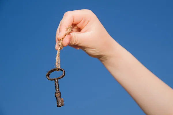 Child hand holding an old key on a string — Stock Photo, Image