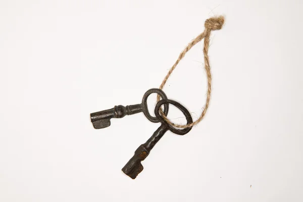 A lot vintage keys on a rope on a white background — Stock Photo, Image