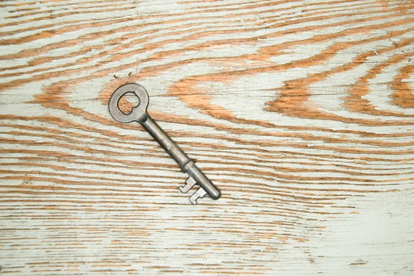 Old key from the lock on a wooden texture — Stock Photo, Image