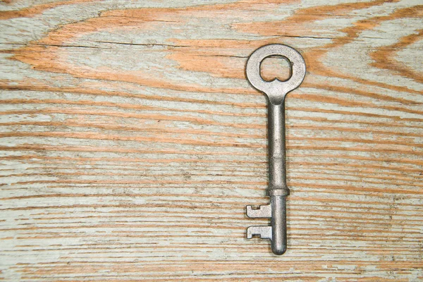 Old key from the lock on a wooden texture — Stock Photo, Image