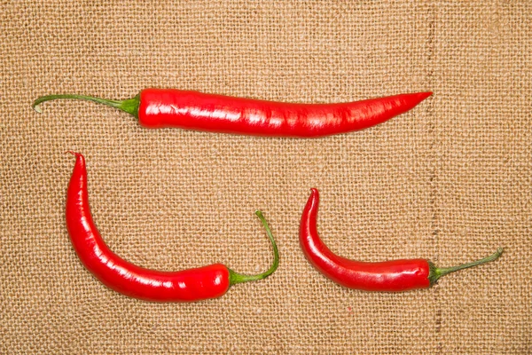Tre peperoncini rossi caldi Cile su vecchio panno — Foto Stock