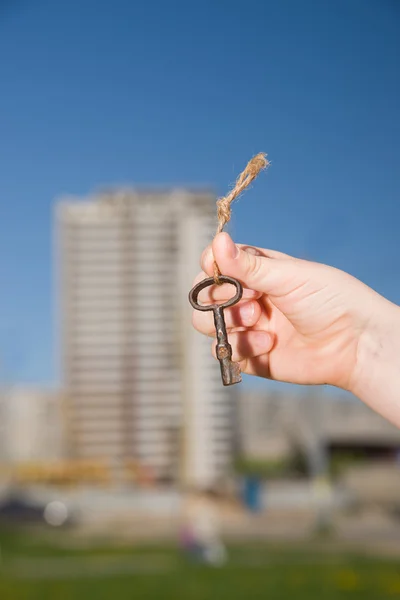 Child hand holding an old keys to the house against the sky — Stock Photo, Image