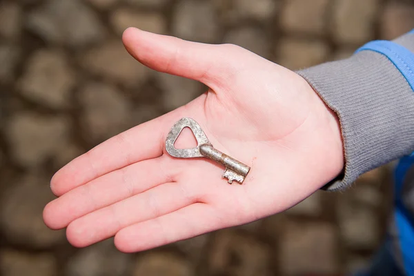 Child's hand holding one old key — Stock Photo, Image