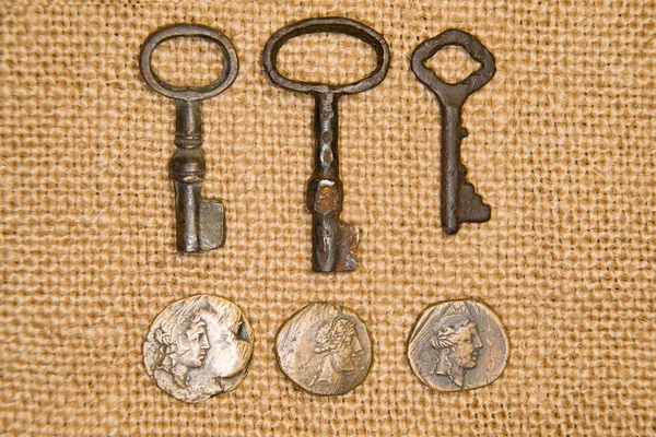 A lot vintage keys from the locks and coins on old cloth — Stock Photo, Image