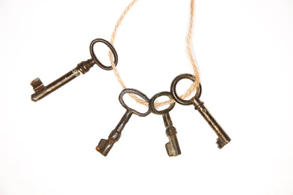 A lot vintage keys on a rope on white background — Stock Photo, Image