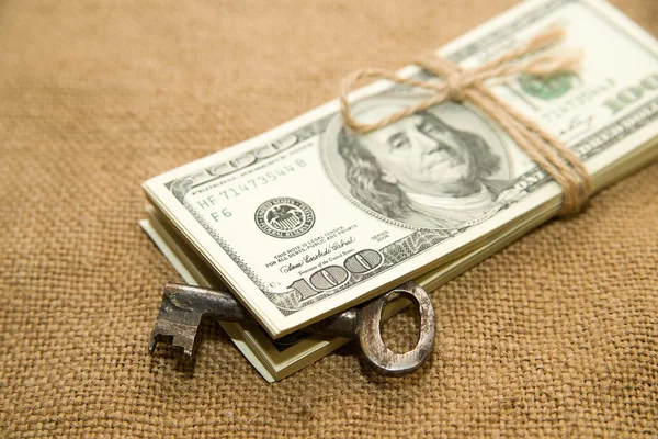 One pack of dollars and key on an old cloth — Stock Photo, Image