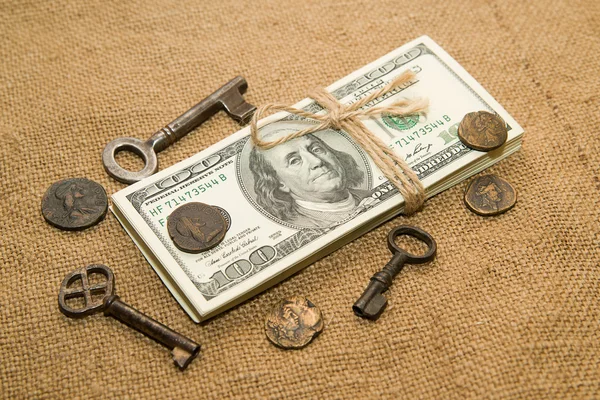 Um pacote de dólares, moedas e chaves em um pano velho — Fotografia de Stock