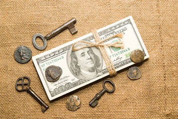 One pack of dollars, coins and keys on an old cloth — Stock Photo, Image