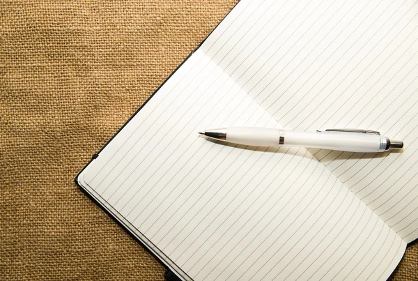 Geopende notebook en pen op de oude weefsel — Stockfoto