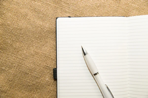 Cuaderno abierto y bolígrafo en el tejido viejo — Foto de Stock