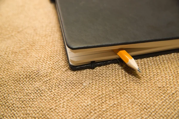 Cuaderno y lápiz en el tejido viejo — Foto de Stock