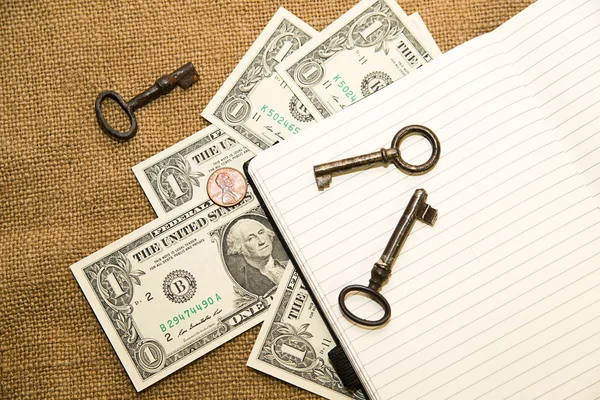 Opened notebook, keys and money on the old tissue — Stock Photo, Image