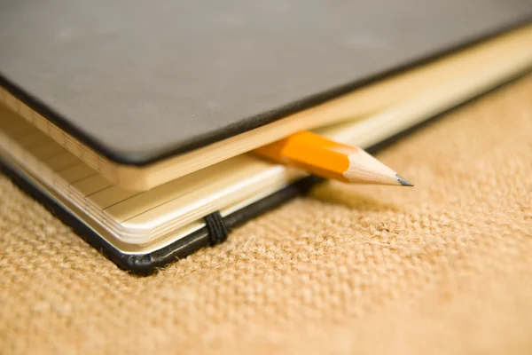 Caderno e lápis no tecido antigo — Fotografia de Stock