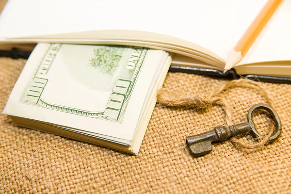 Opened notebook, pencil, key and money on the old tissue — Stock Photo, Image