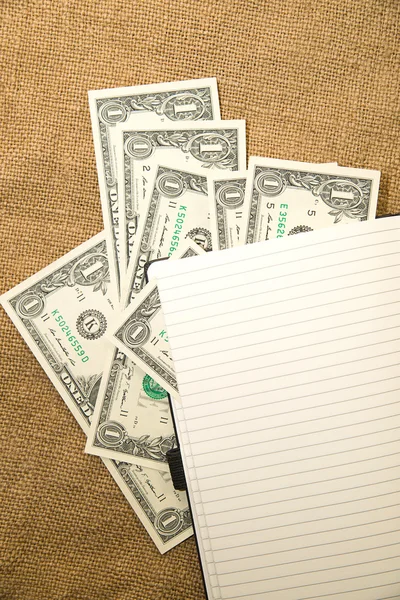 Opened notebook and money on the old tissue — Stock Photo, Image