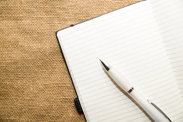 Cuaderno abierto y bolígrafo en el tejido viejo — Foto de Stock