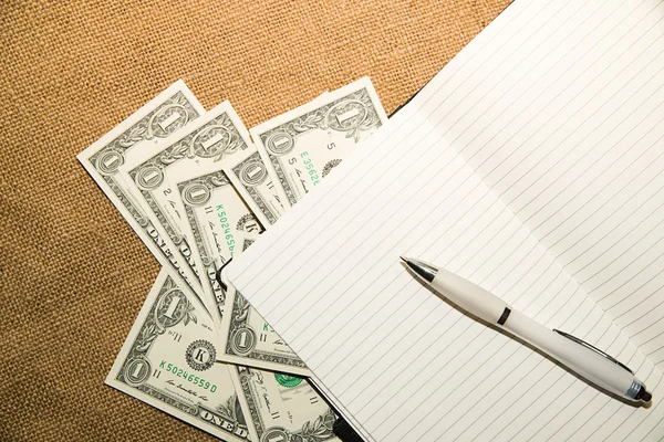 Cuaderno abierto, bolígrafo y dinero en el tejido viejo — Foto de Stock