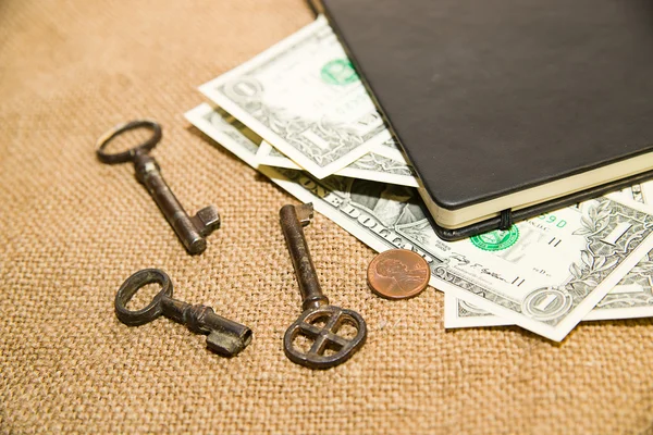 Notebook, key and money on the old tissue — Stock Photo, Image