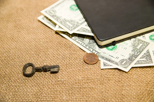 Notebook, key and money on the old tissue — Stock Photo, Image