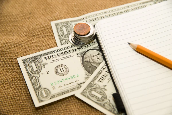 Caderno aberto, lápis e dinheiro no tecido antigo — Fotografia de Stock