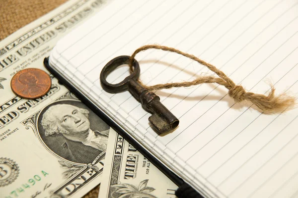 Opened notebook, key and money on the old tissue — Stock Photo, Image