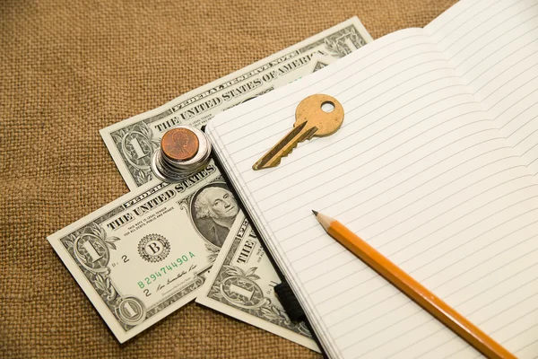 Caderno aberto, lápis, chave e dinheiro no tecido antigo — Fotografia de Stock
