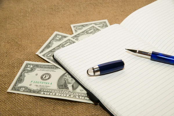 Opened notebook, pen and money on the old tissue — Stock Photo, Image