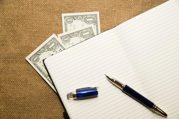 Opened notebook, pen and money on the old tissue — Stock Photo, Image