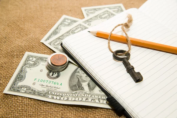 Opened notebook, pencil, key and money on the old tissue — Stock Photo, Image
