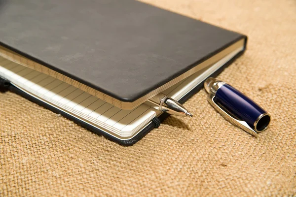Ноутбук и ручка на старой ткани — стоковое фото