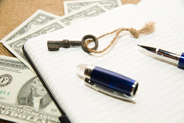 Opened notebook, pen, key and money on the old tissue — Stock Photo, Image