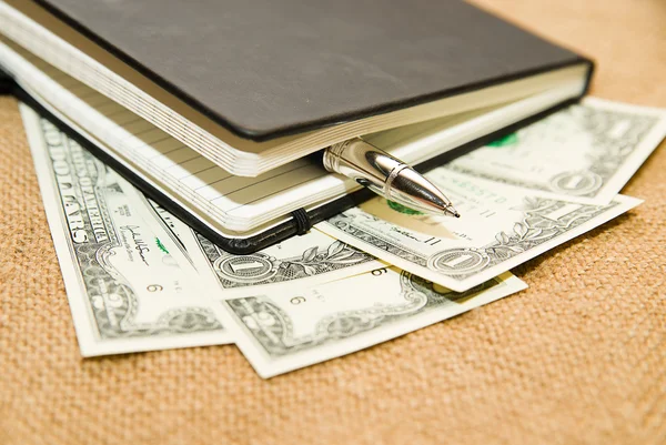 Notebook, pen en geld op de oude weefsel — Stockfoto