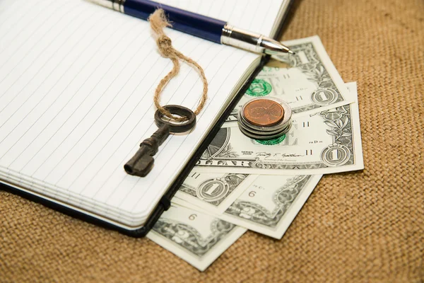 Opened notebook, pen, key and money on the old tissue — Stock Photo, Image