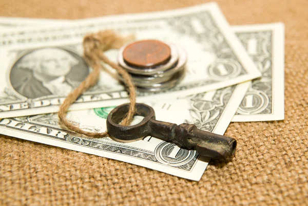 US dollars banknotes, coins and key on an old cloth — Stock Photo, Image