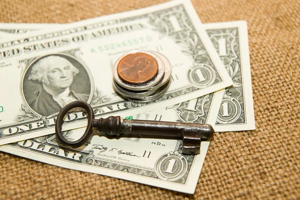 Bize dolar banknotlar, sikke ve eski bir kumaş üzerine anahtarı — Stok fotoğraf