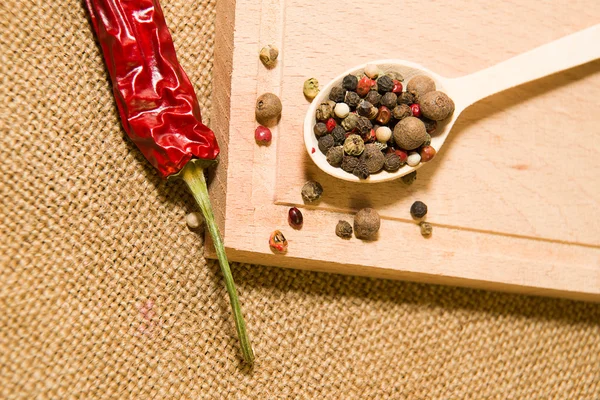 Cucchiaio riempito con una miscela di grani di pepe sono su un legno — Foto Stock