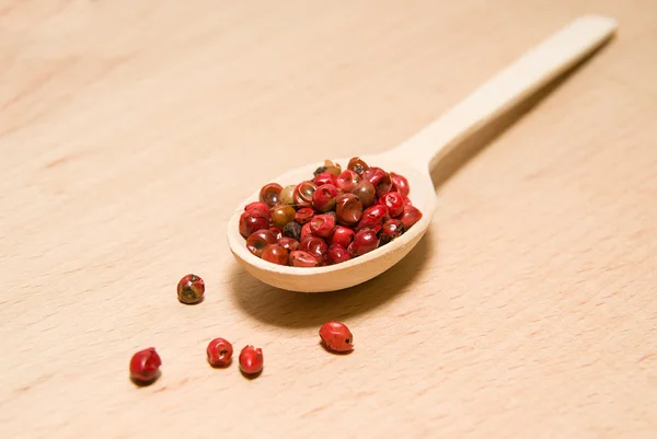 Lepel gevuld met een mengsel van granen van peper zijn op een houten — Stockfoto