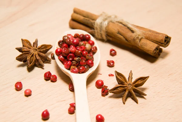 Ложка, зерна перцю, кориці та зіркового анісу на дерев'яному супі — стокове фото