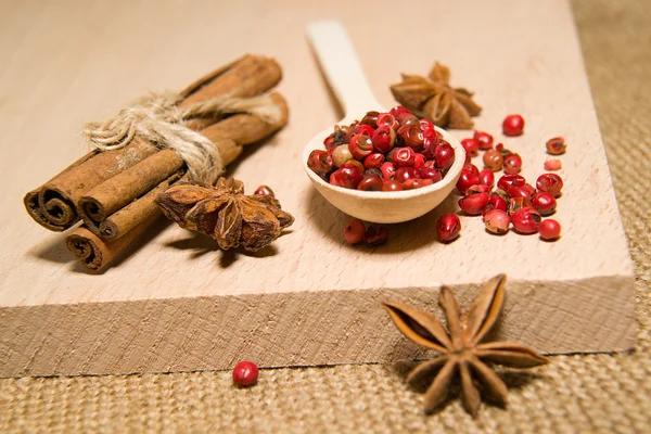 Ложка, зерна перцю, кориці та зіркового анісу на дерев'яному серці — стокове фото