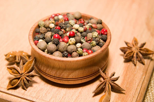 Les grains de poivre et d'anis étoilé sur une surface en bois — Photo