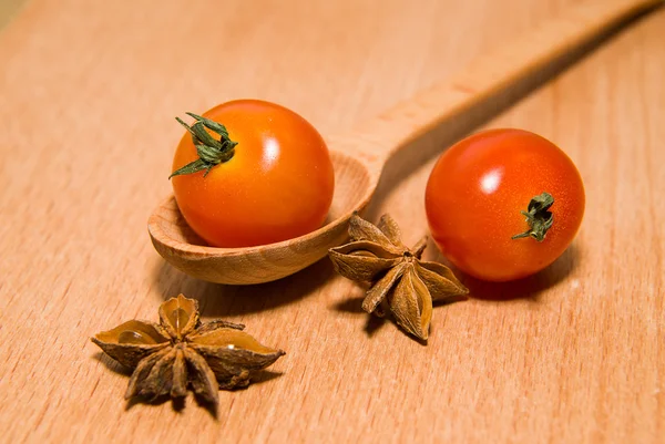 Tomates rojos en cuchara y anís estrellado sobre una superficie de madera — Foto de Stock